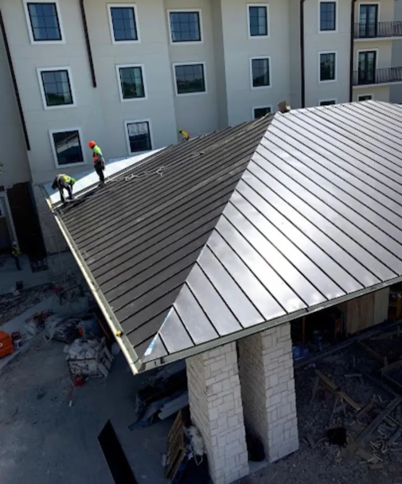 Crew installing standing seam metal roof panels on a commercial project in Griffith